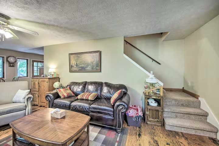 Living room with leather sofa, wooden coffee table, and stairs leading up.