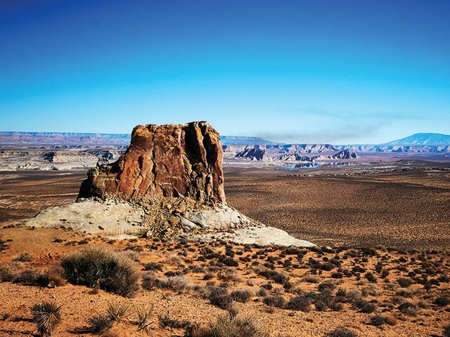 A desert landscape with mountains in the background and a blue sky with clouds.