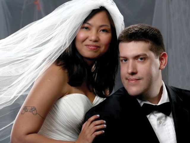 A bride and groom pose for a picture with the bride wearing a veil