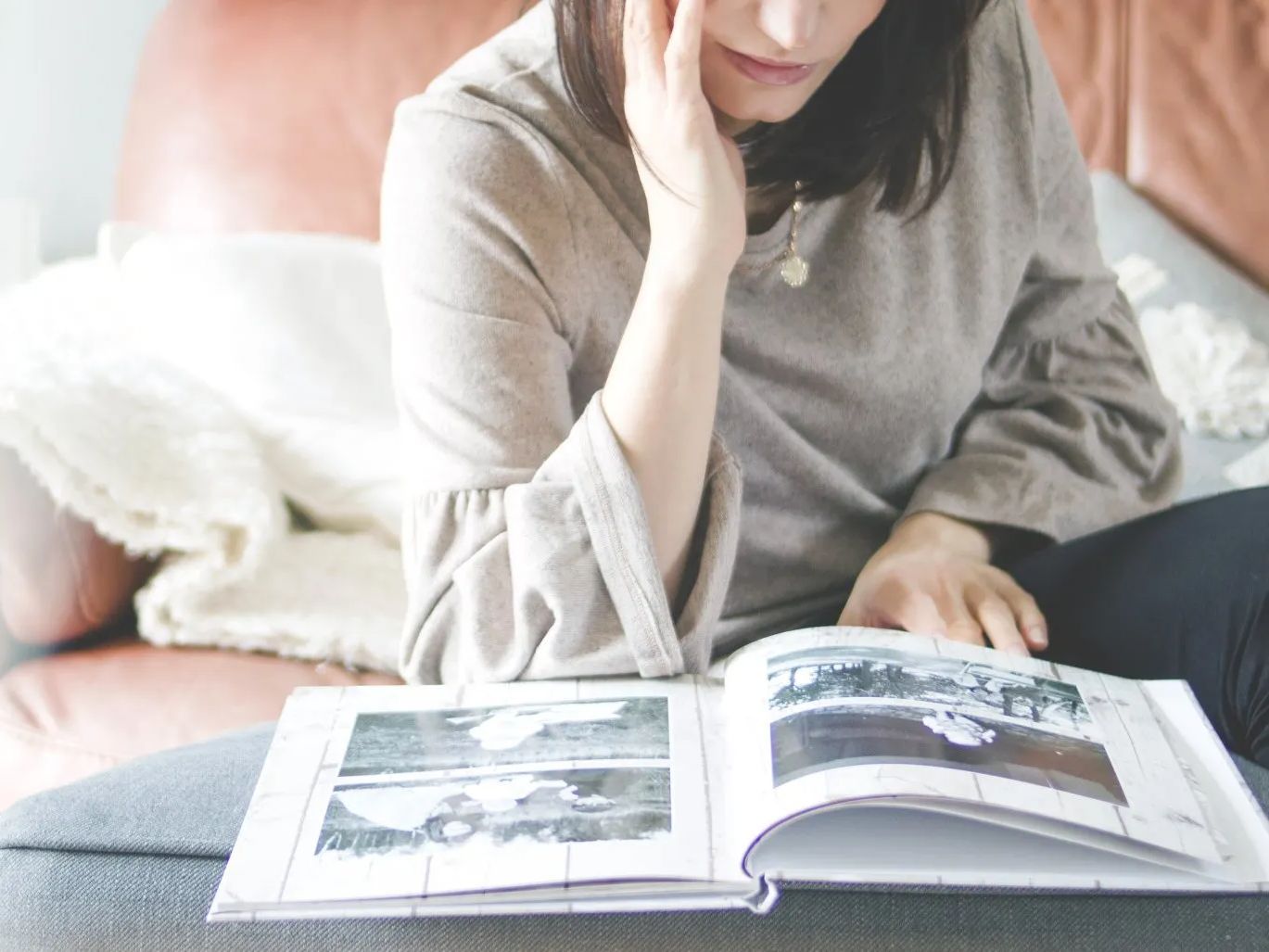 a woman is sitting on a couch reading a book .