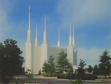 White temple with multiple spires against a cloudy sky, surrounded by trees and shrubs.