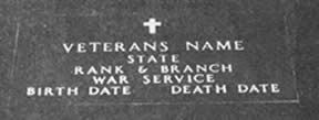 Close-up of a veteran's tombstone with a cross. Text on the stone includes: name, state, rank, war, birth & death dates.