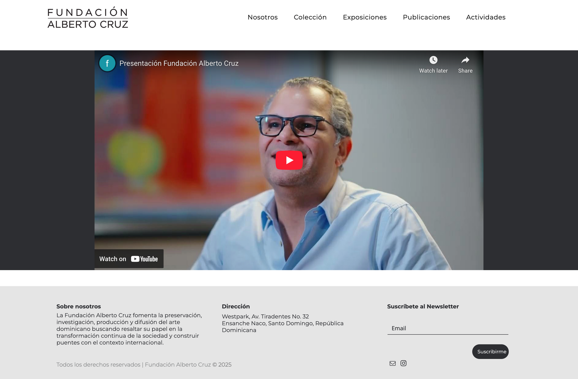 A man wearing glasses is smiling in a video on a website.