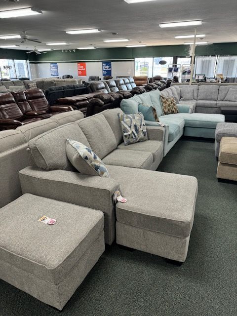 A furniture showroom with various couches and ottomans in shades of gray and blue.