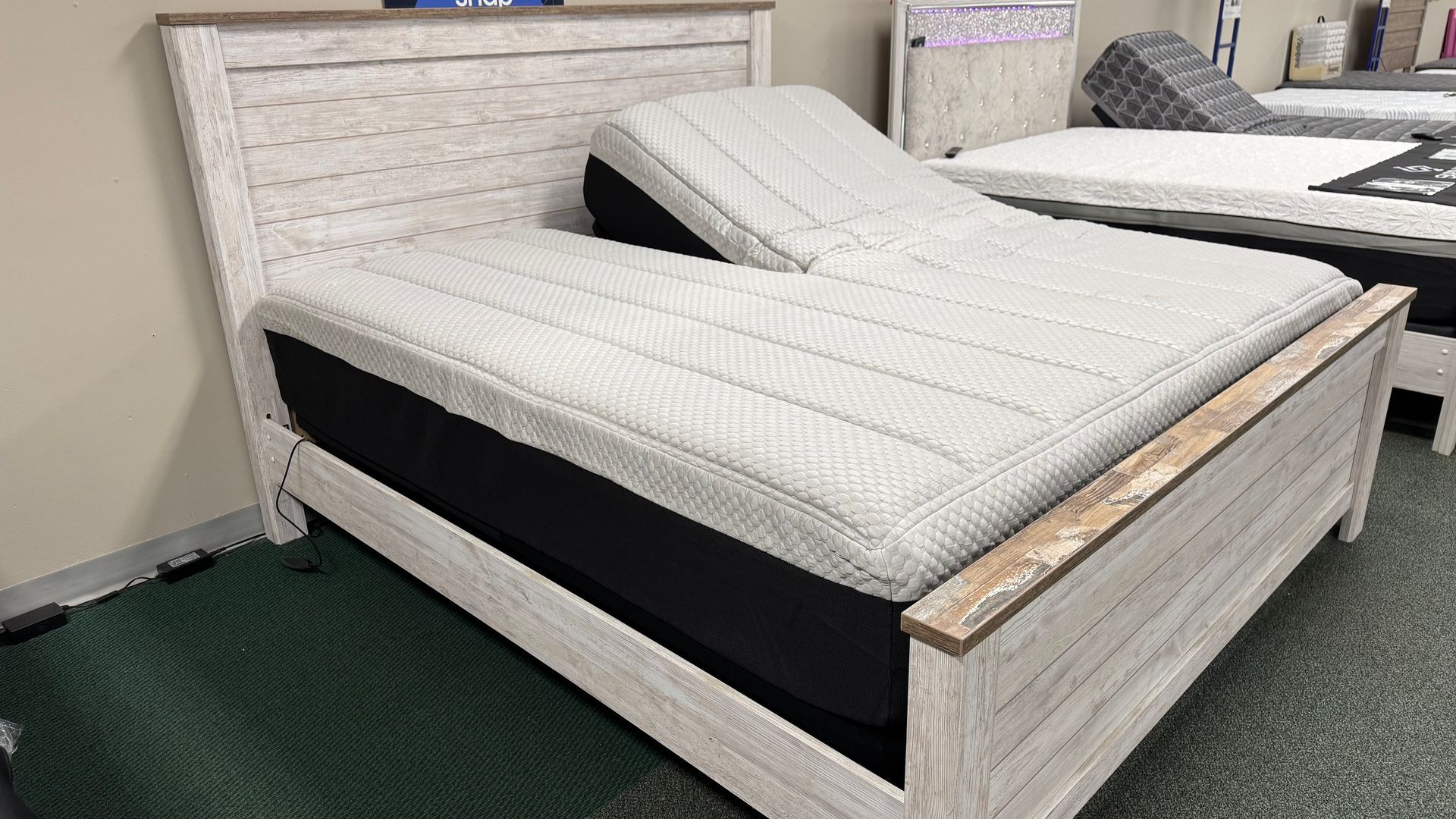 Queen-sized bed with a gray and white patterned mattress on a dark brown wooden frame in a room.