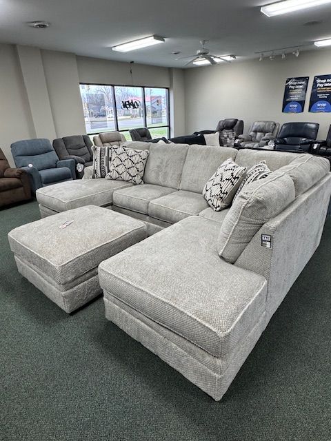 U-shaped light gray sectional sofa with two ottomans in a furniture store.