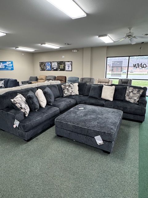 Blue sectional sofa with ottoman in a furniture store.