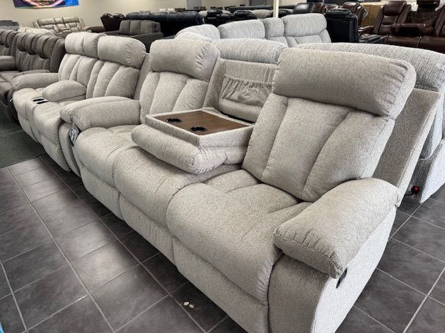 Light gray reclining sofa with built-in console and cup holders in a furniture store.