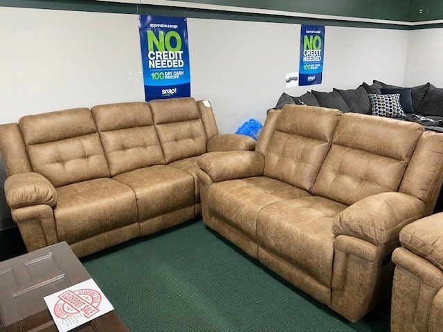 Tan leather reclining sofa set in a furniture store.