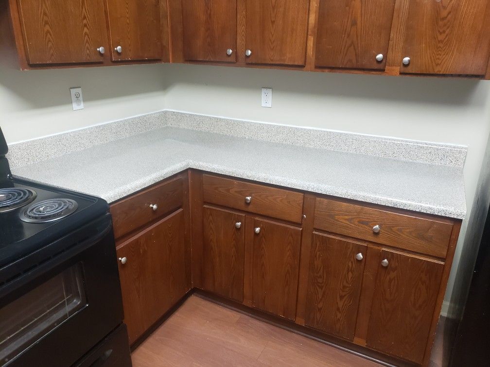 A kitchen with wooden cabinets , a black stove , and granite counter tops.