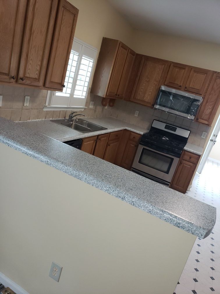 A kitchen with wooden cabinets , stainless steel appliances , granite counter tops and a window.