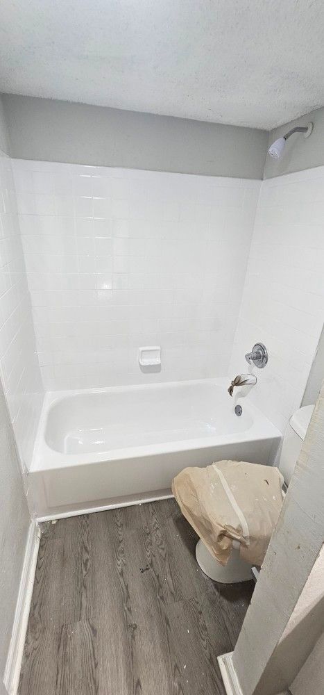 A bathroom with a bathtub , toilet and shower.