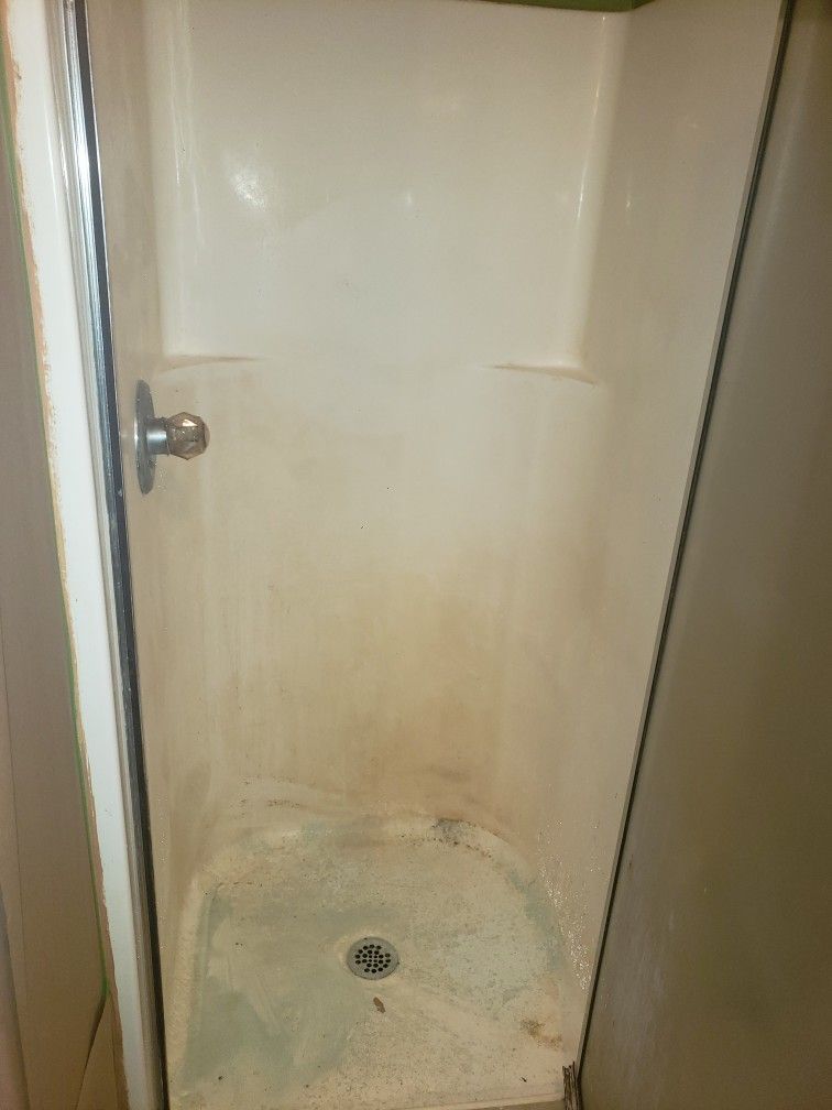 A dirty shower stall with a glass door in a bathroom.