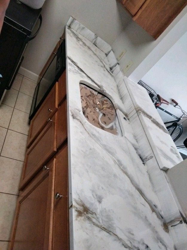 A kitchen with a marble counter top and a sink.