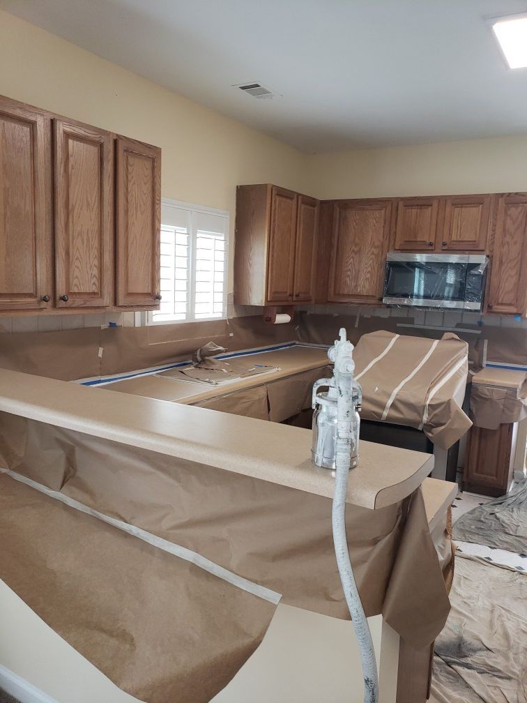 A kitchen with wooden cabinets and a microwave is being painted.