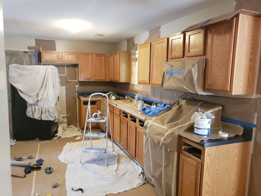 A kitchen is being painted with wooden cabinets and a ladder.