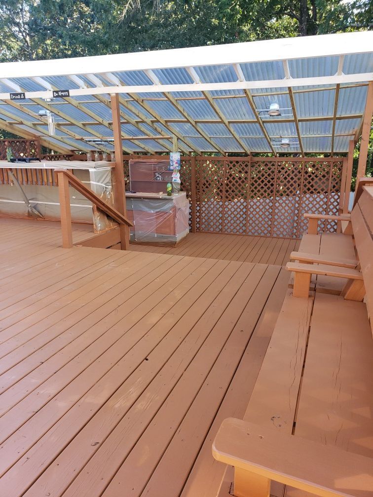 A wooden deck with a bench under a clear roof