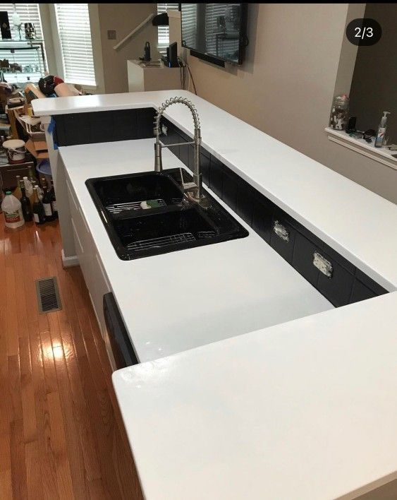 A kitchen with white counter tops and a black sink