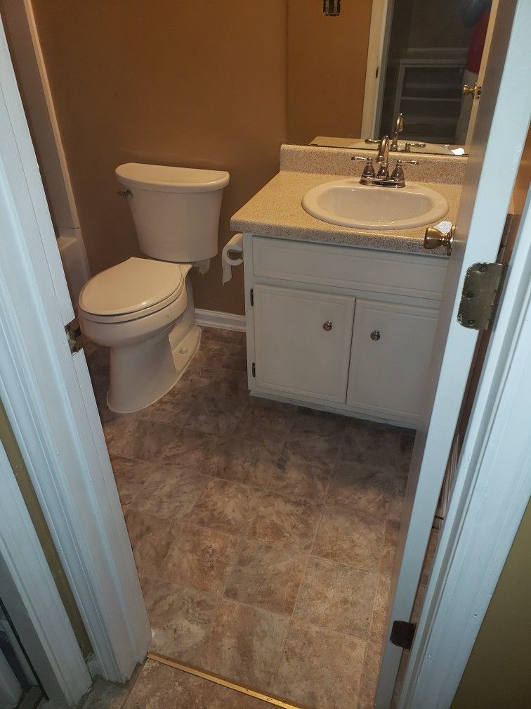 A bathroom with a toilet , sink and mirror.