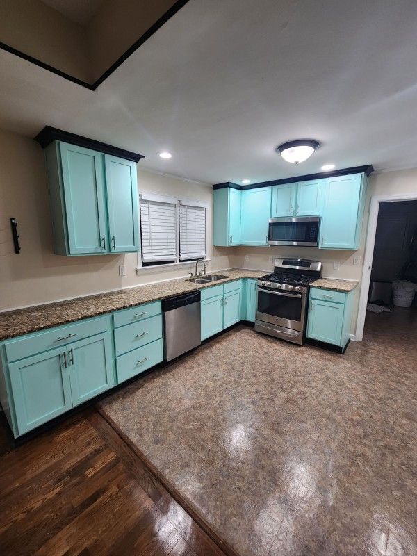 A kitchen with blue cabinets and stainless steel appliances.