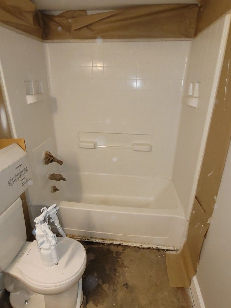 A bathroom with a toilet a bathtub and a spray bottle