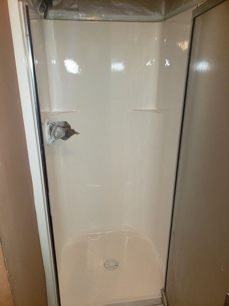 A white shower stall in a bathroom with a glass door.