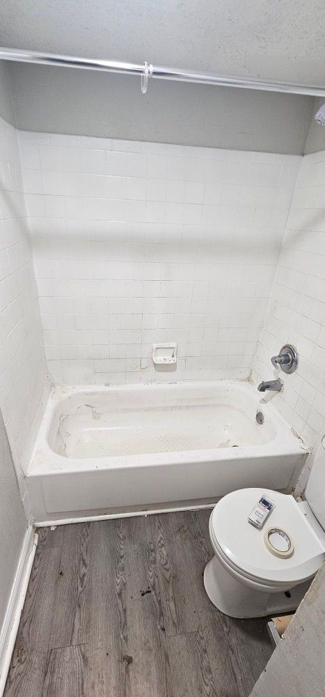 A bathroom with a tub , toilet and shower.