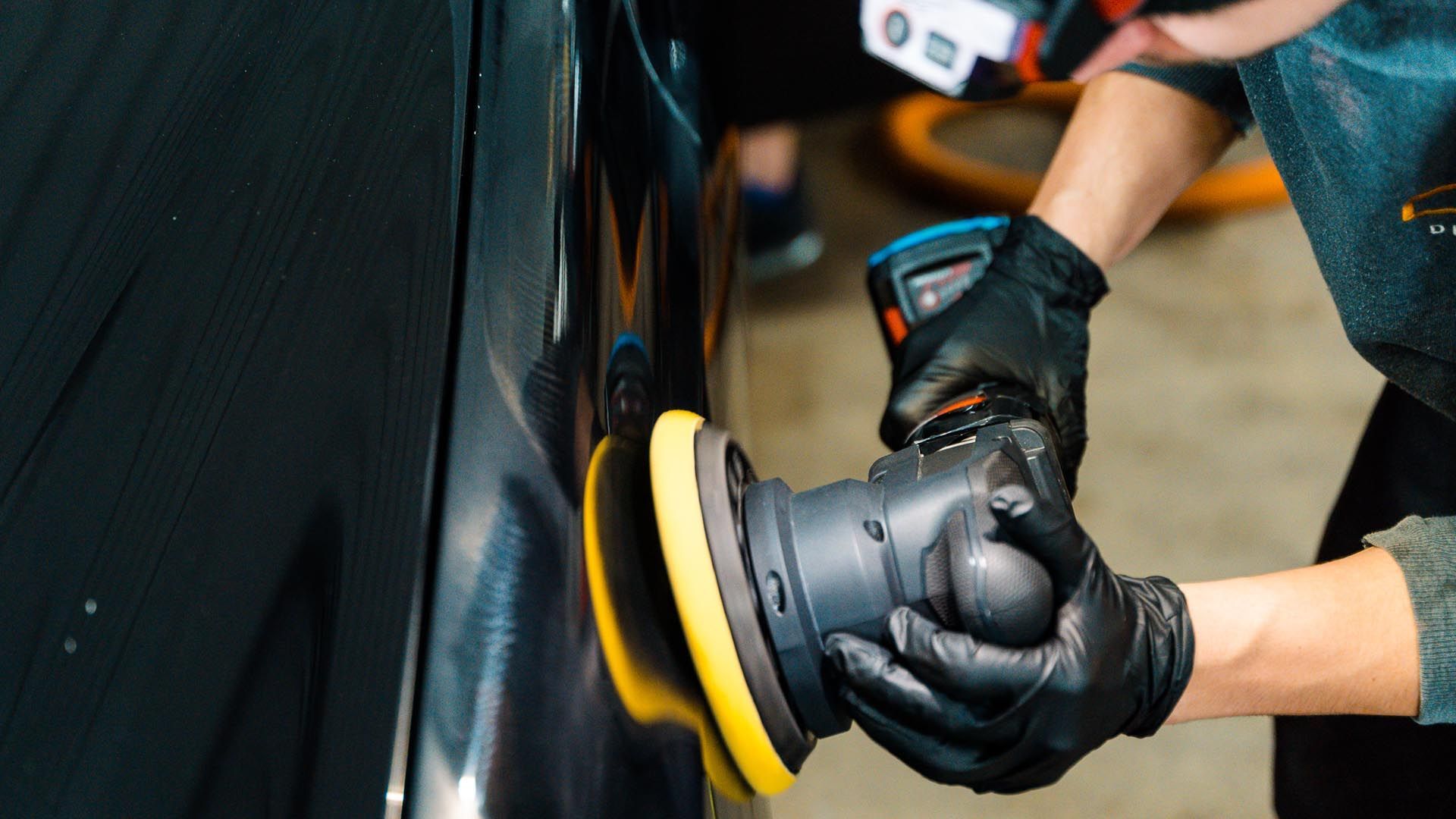 A person is polishing a car with a machine.