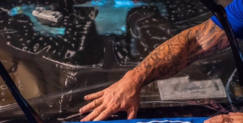 A man is applying window tinting to a car windshield.