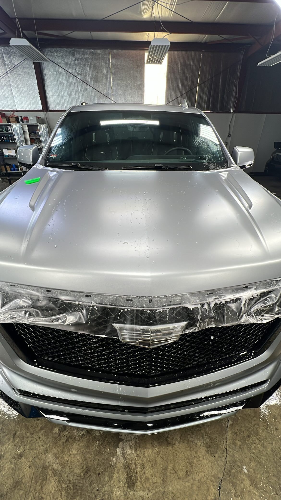 A silver car is wrapped in aluminum foil in a garage.
