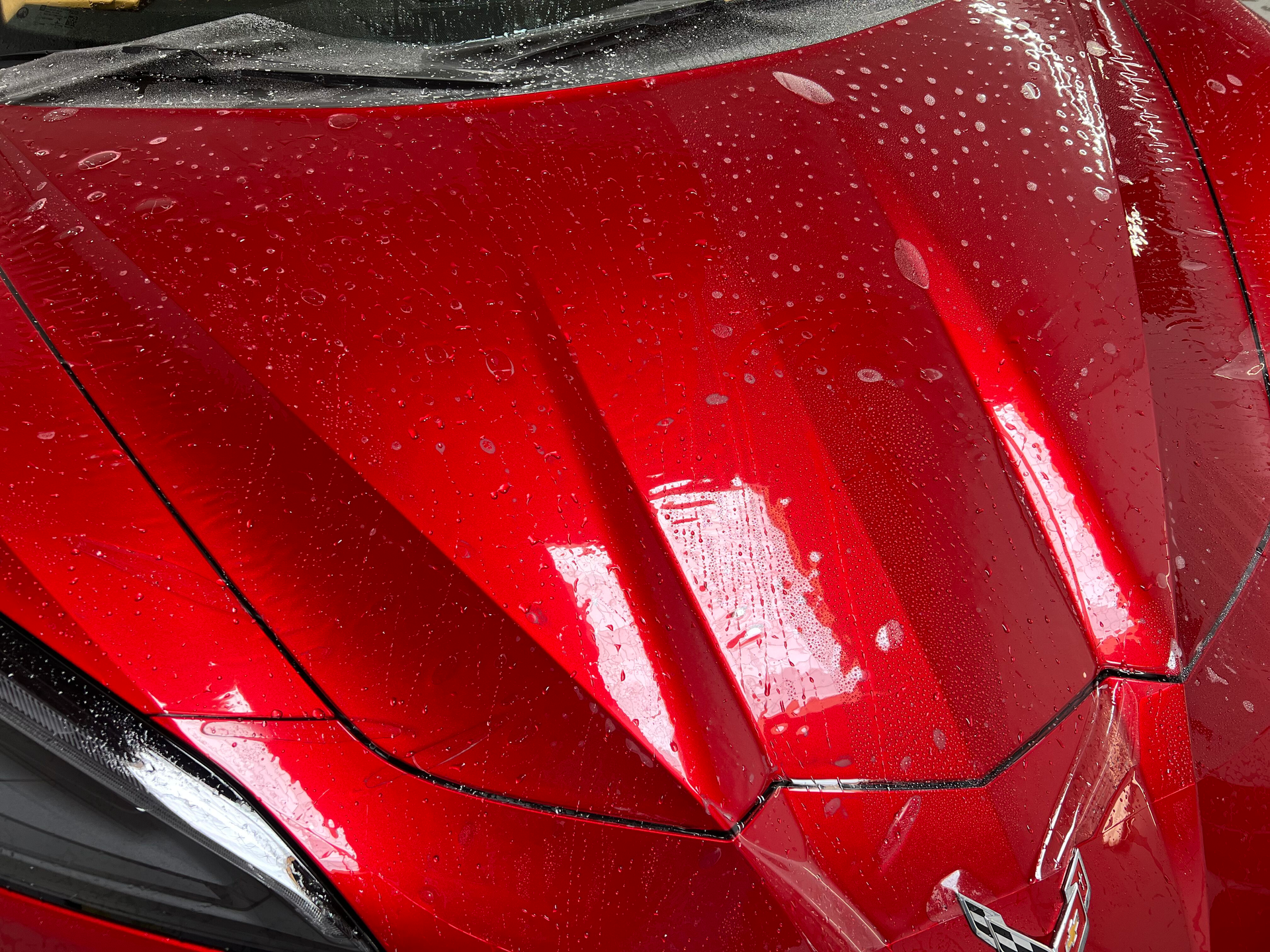A close up of a red car with water drops on it