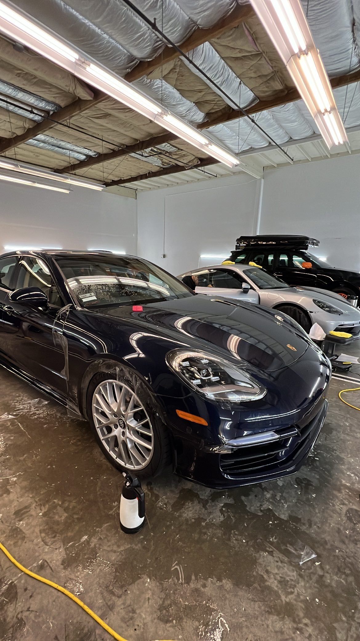 A blue porsche panamera is being polished in a garage.
