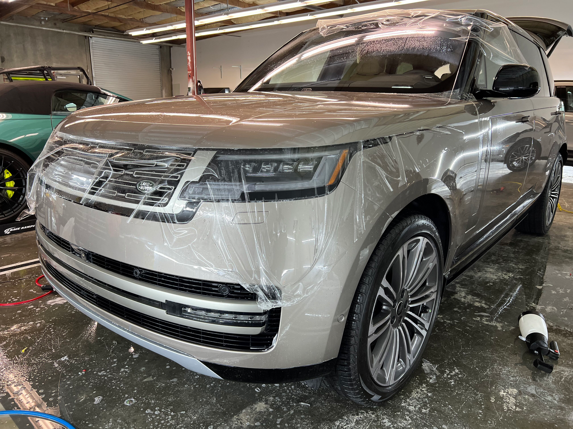 A range rover is covered in plastic wrap in a garage.