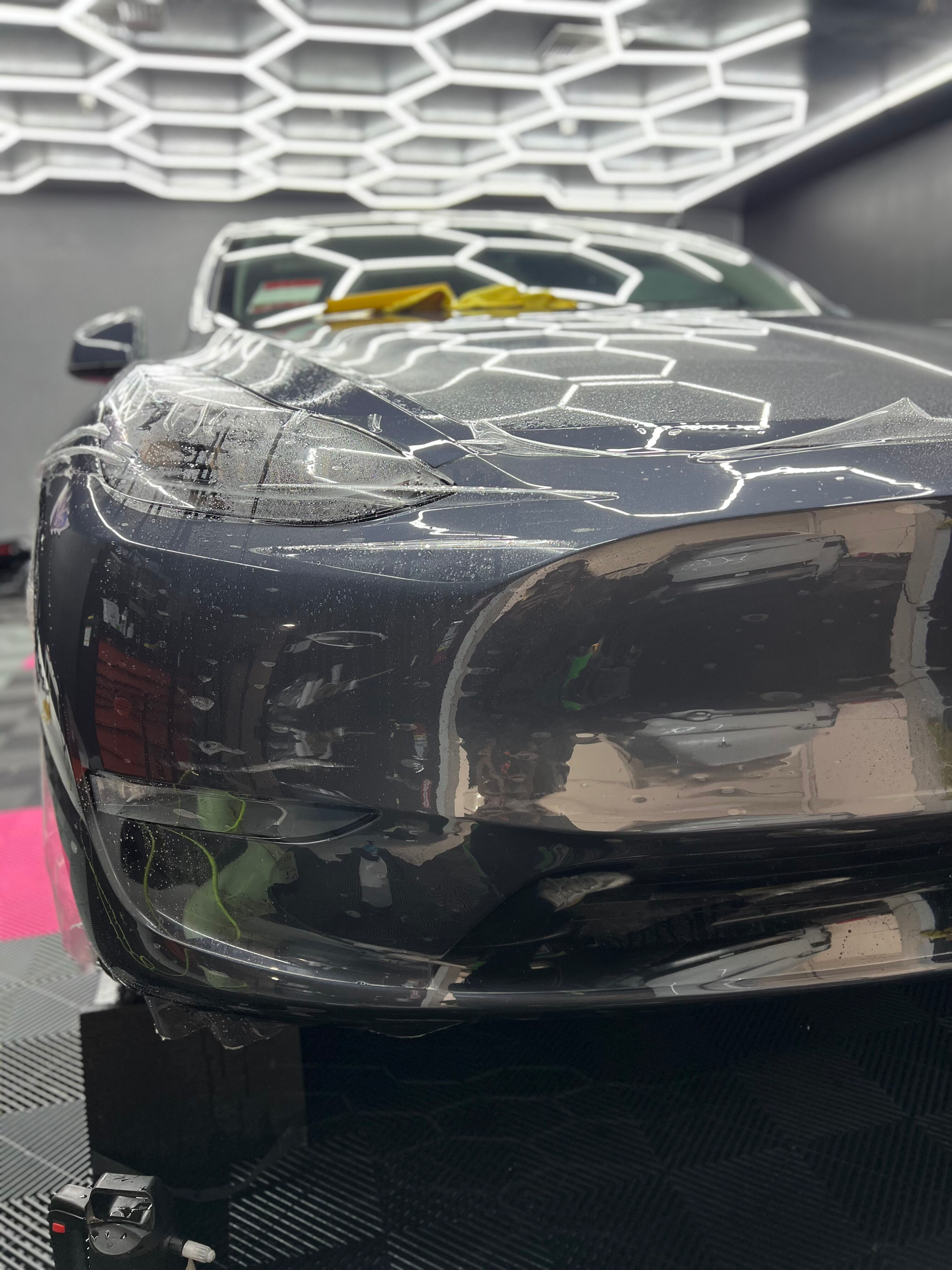 A black car is sitting on a table in a garage.