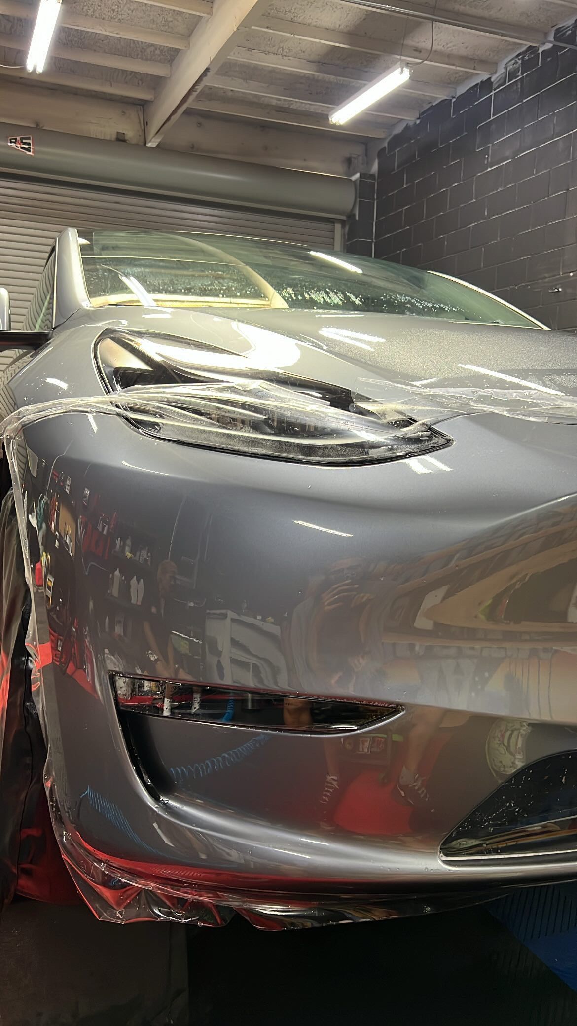 A tesla model 3 is being washed in a garage.