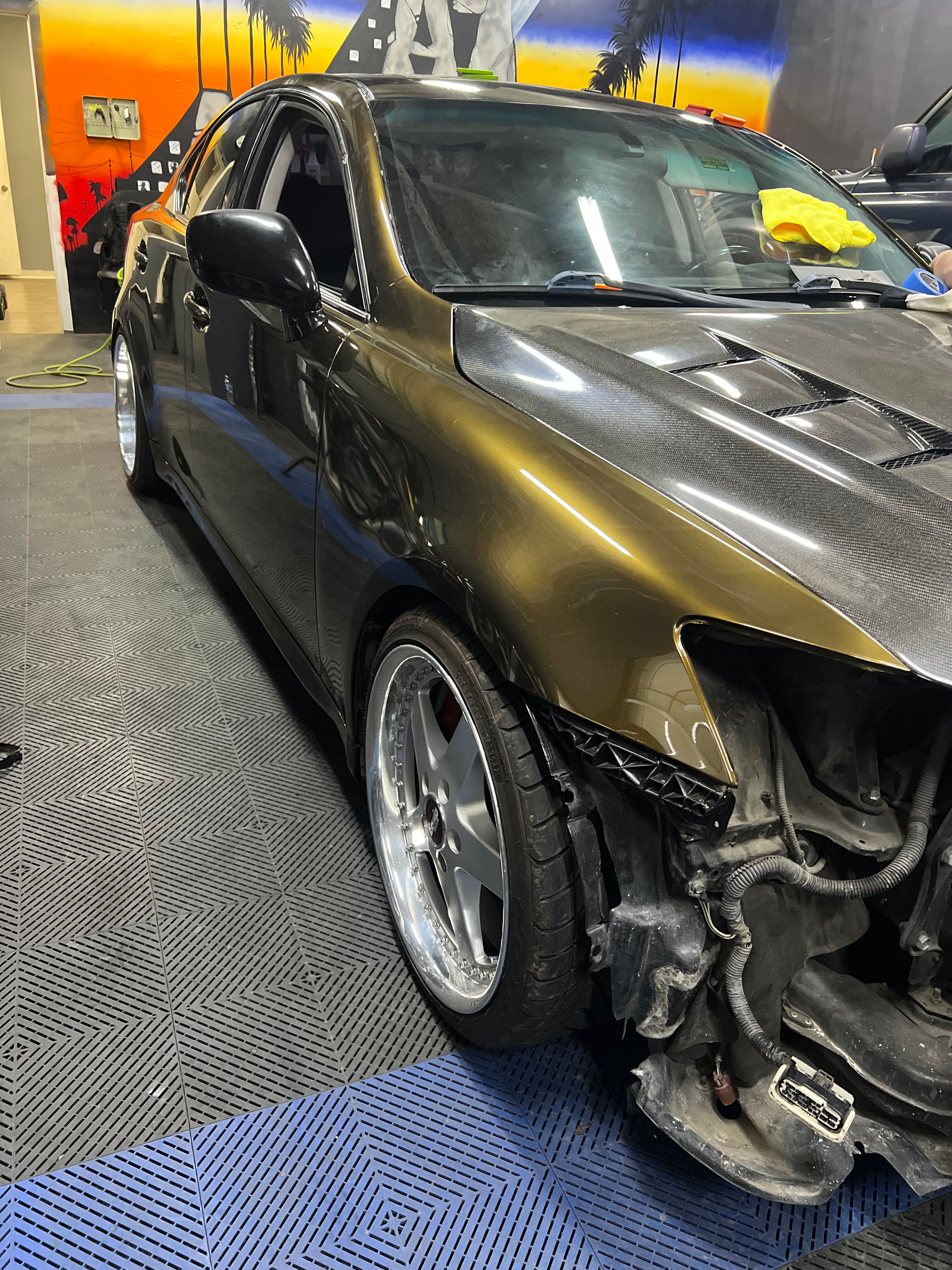 A car with a damaged front end is parked in a garage.