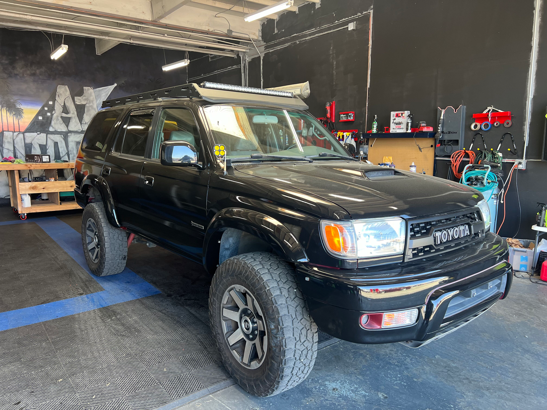 A black toyota 4runner is parked in a garage.