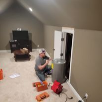 A man is working on a water heater in a living room.
