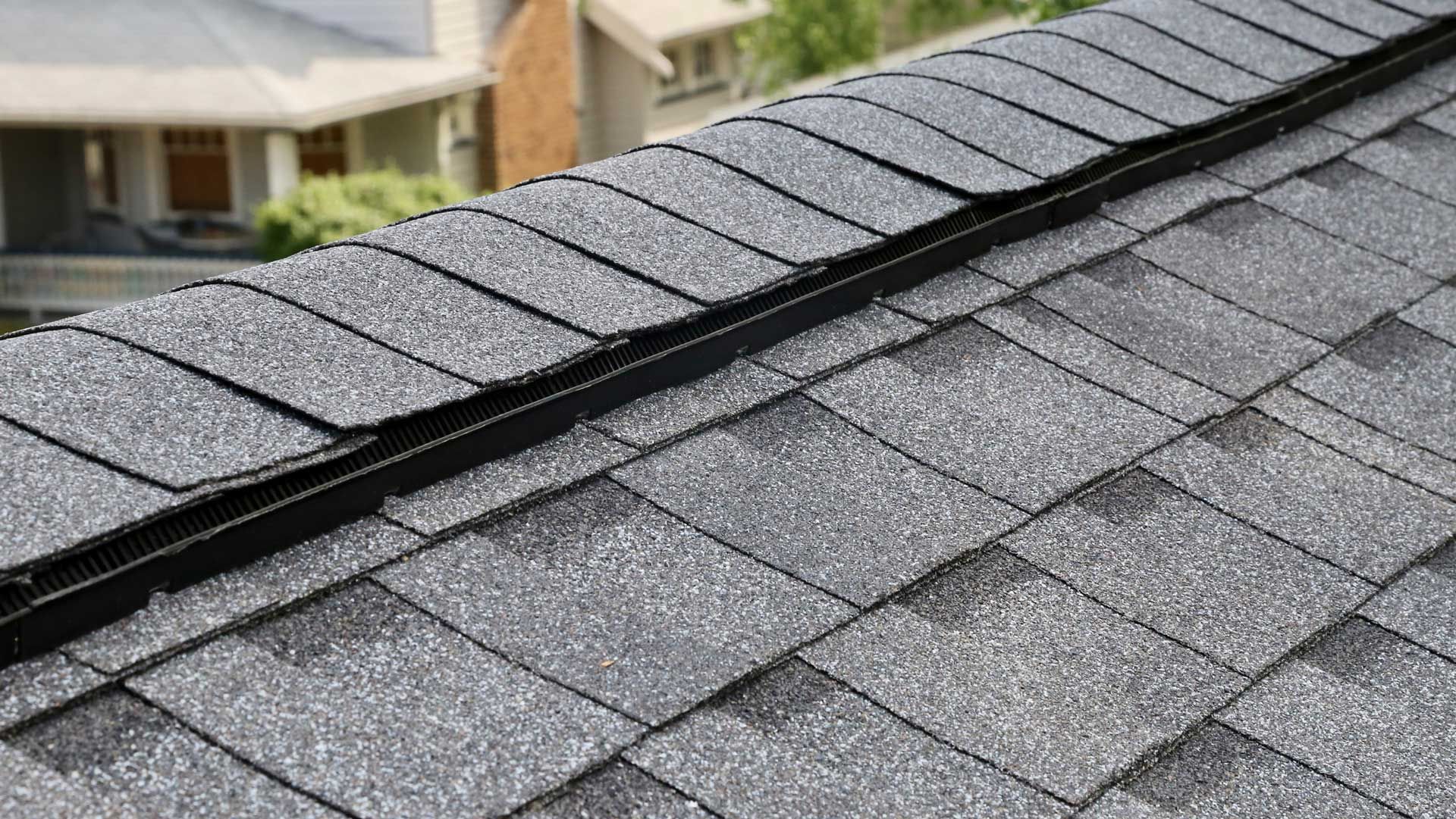 Close-up of a gray shingle roof with a black metal valley.
