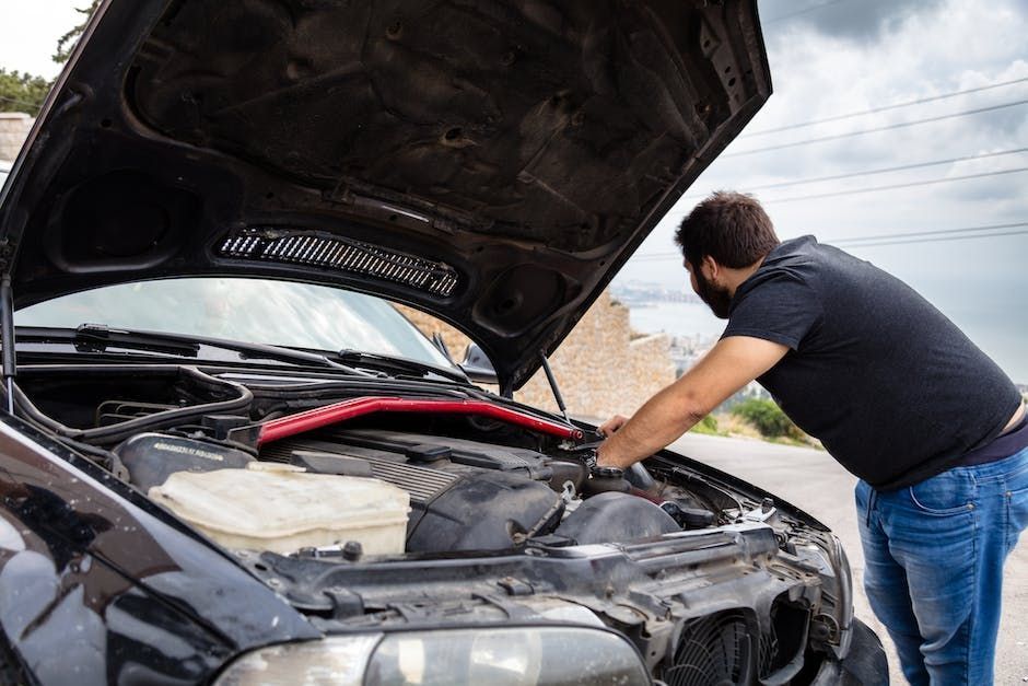 A Man is Looking Under the Hood of a Broken Down Car — Automotive All Stars Car Service and Repair i