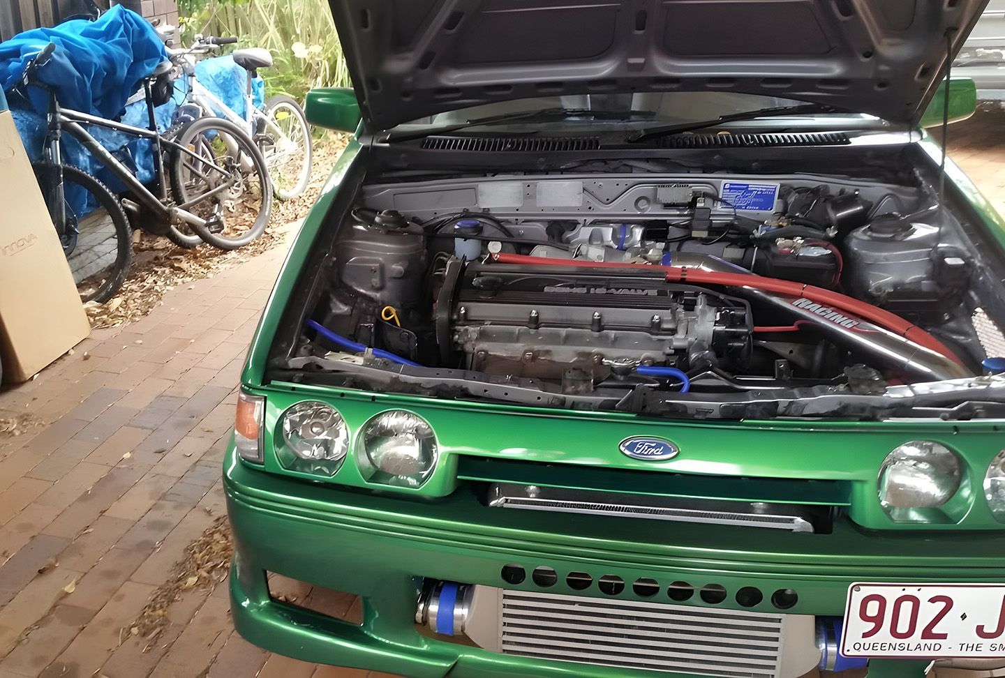Car Battery In Engine Bay Of Green Car With Hood Open
