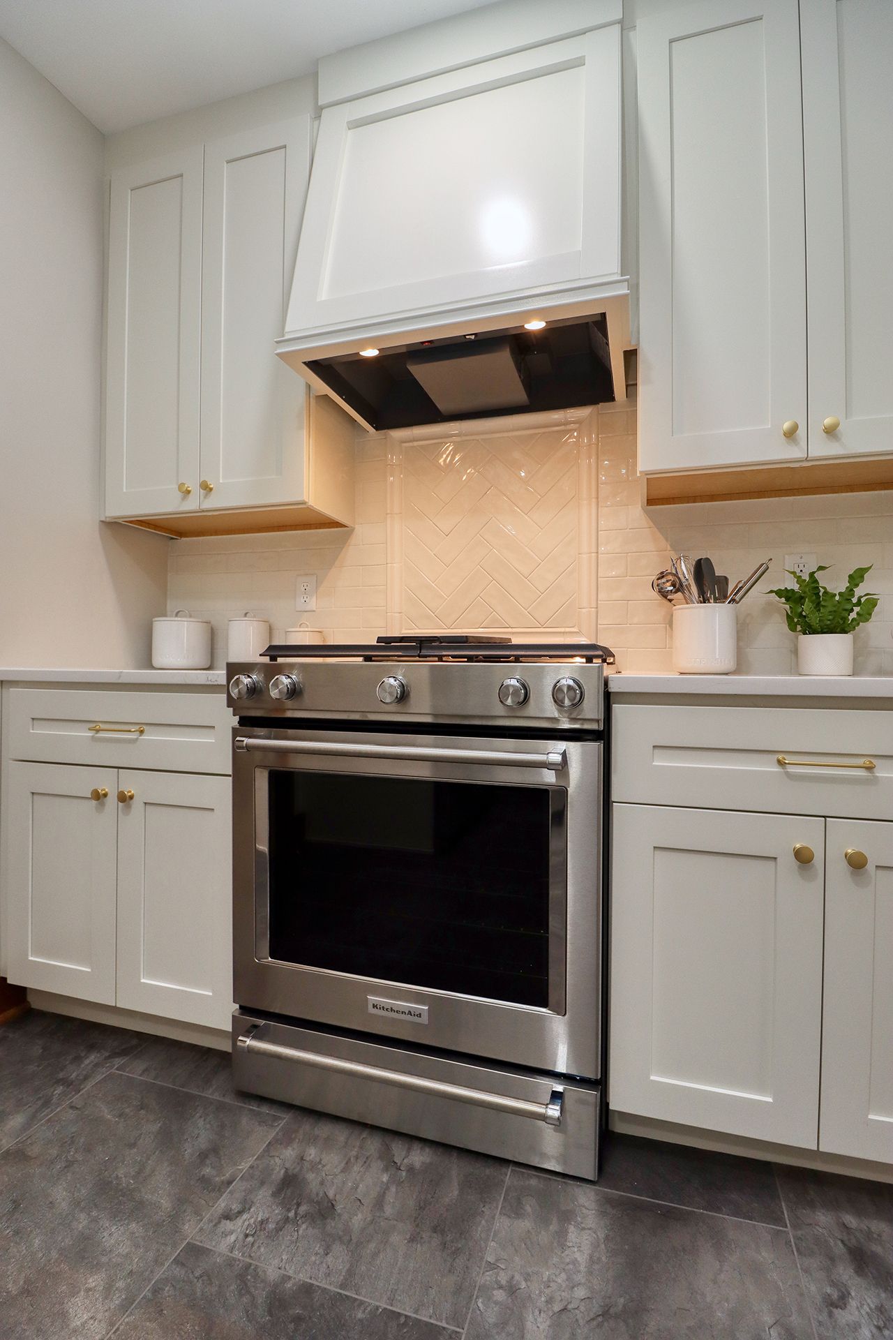 Stainless steel range in a white kitchen with light wood accents and backsplash.
