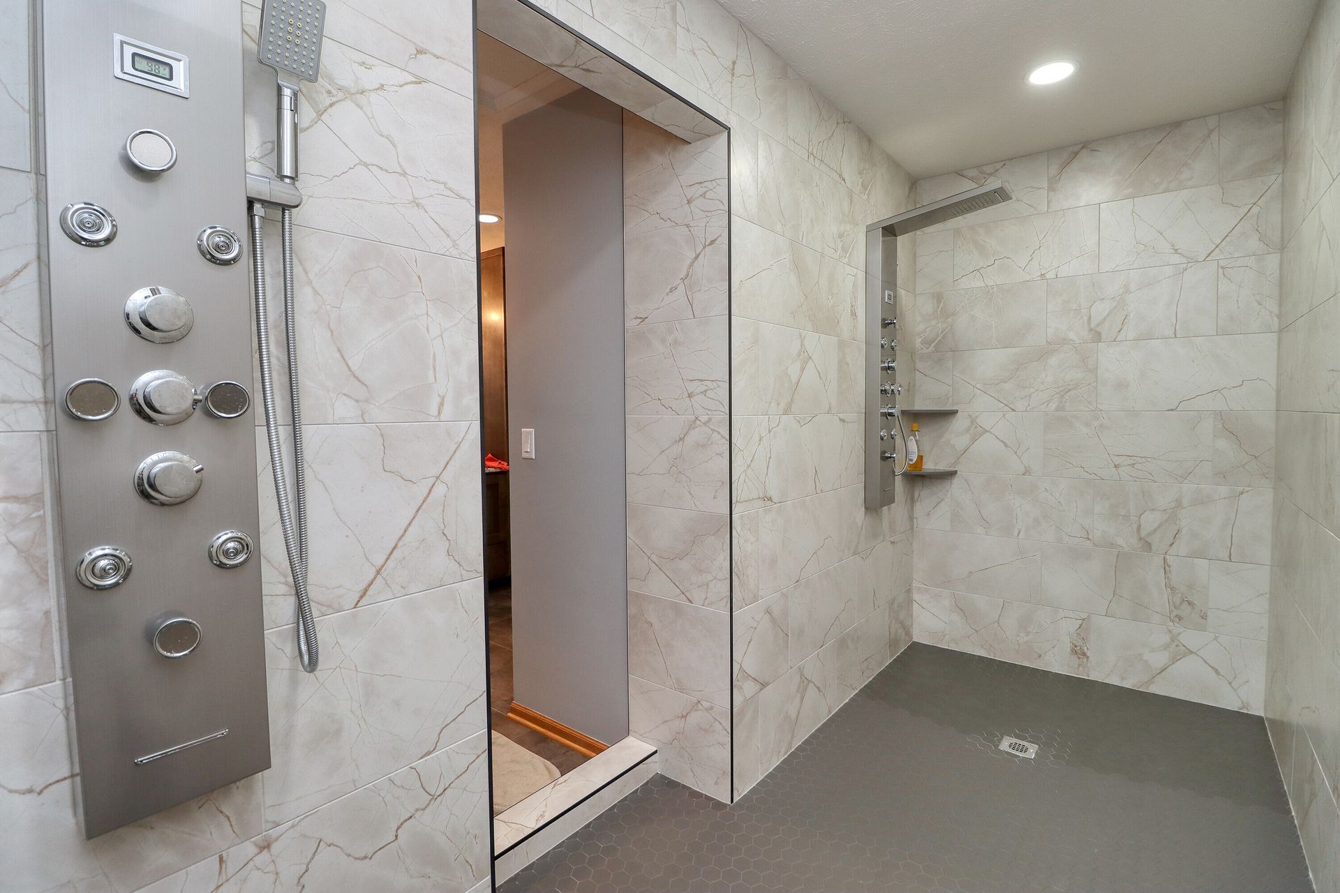 Modern accessible shower with gray floor, tiled walls, and silver shower fixtures.