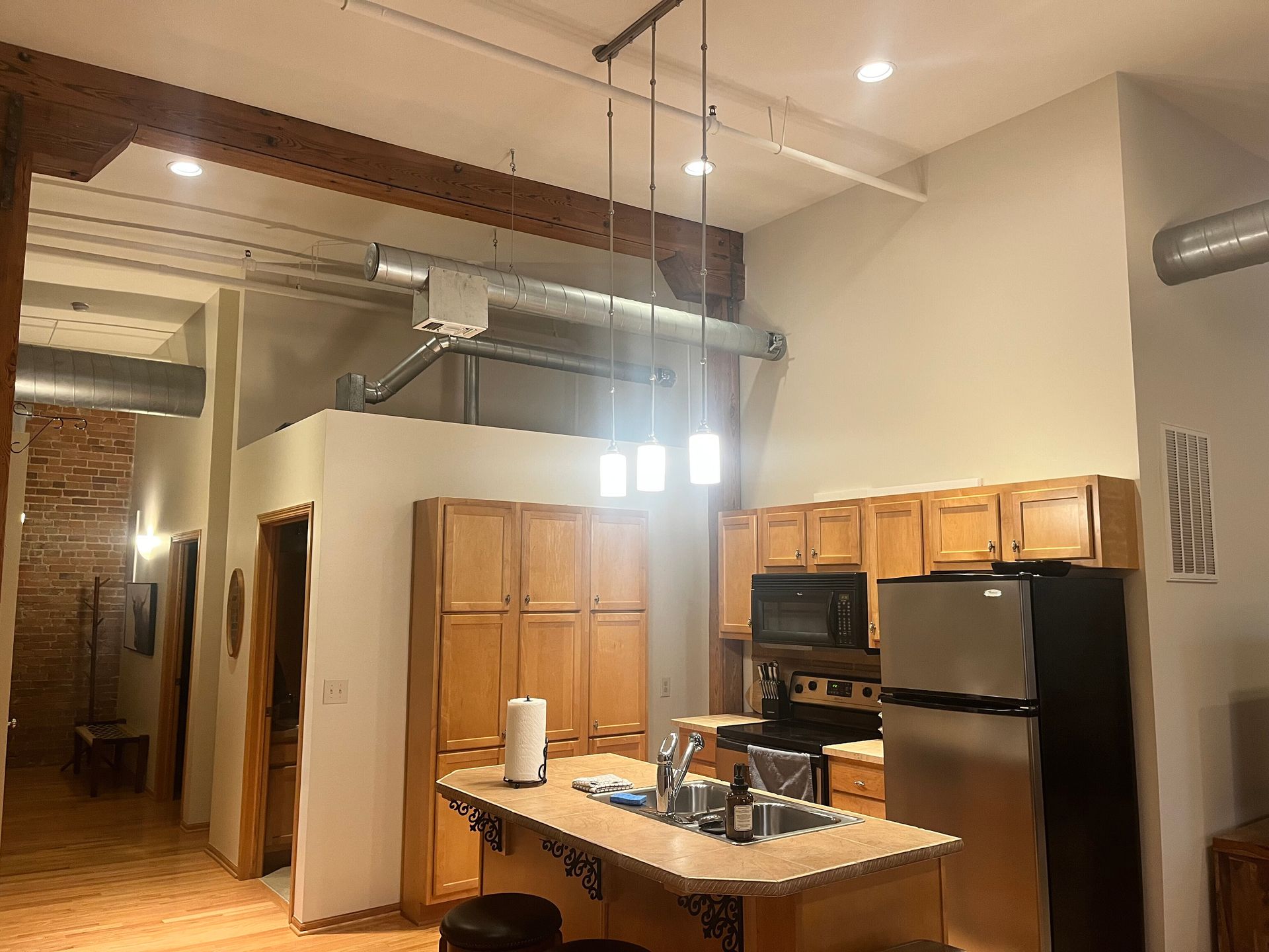 Loft apartment interior with kitchen island, stainless steel appliances, and exposed ductwork.