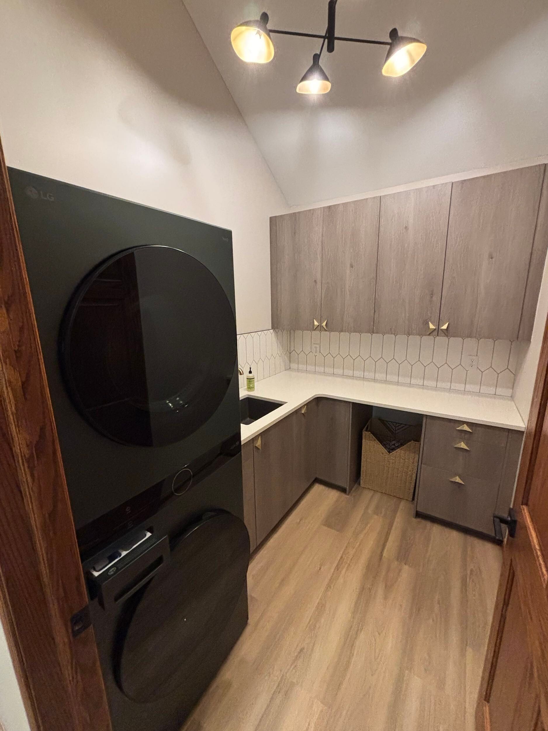 Laundry room with a stacked black washer and dryer, cabinetry, and flooring.