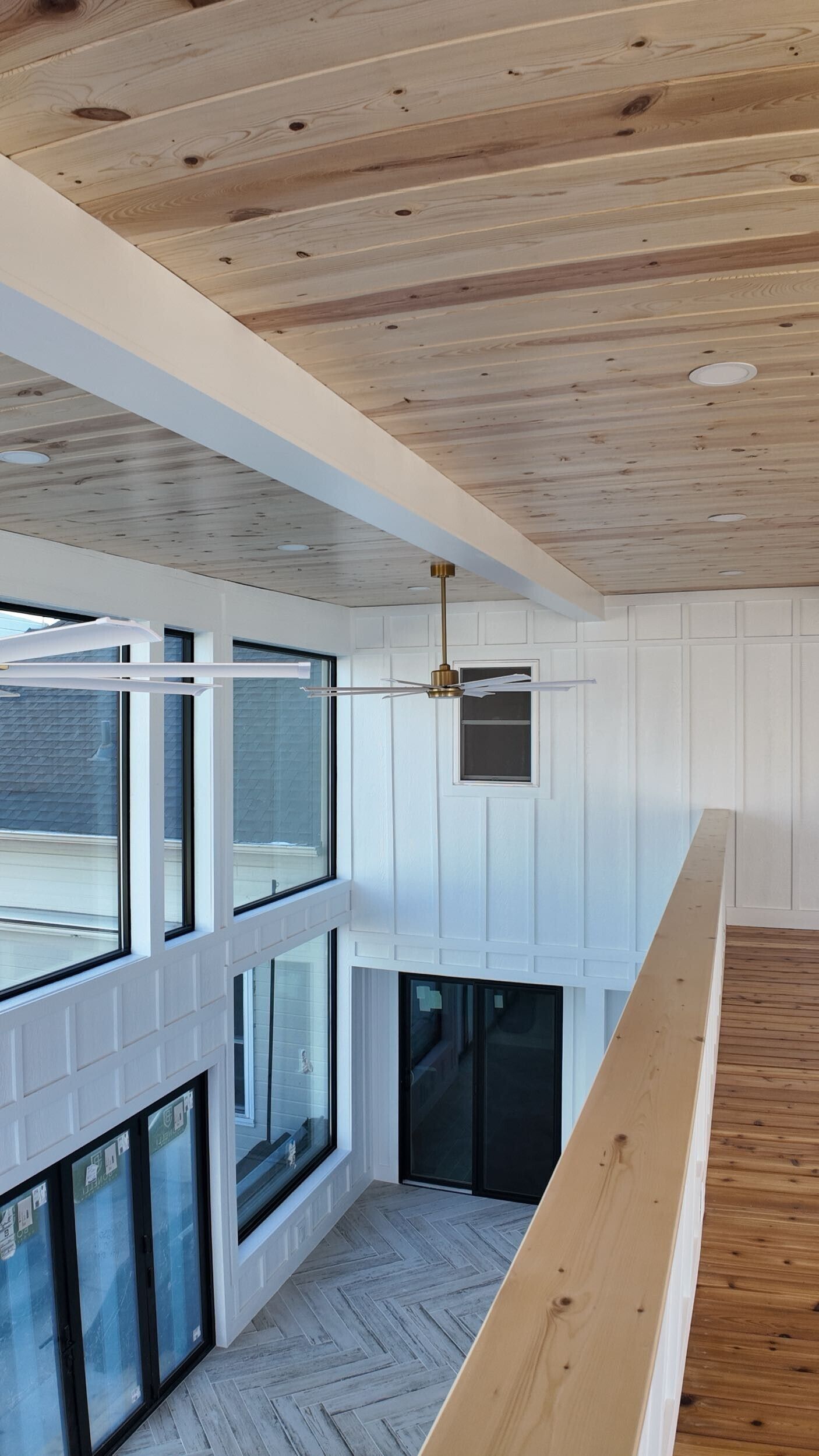 Interior view of a modern loft with a wooden ceiling, white walls, and large windows.