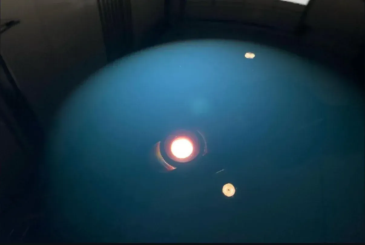 A light is shining on a blue surface in a dark room.
