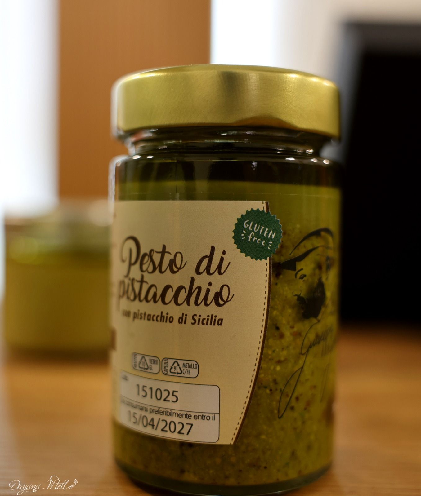 Un vasetto di pesto di pistacchi siciliano con coperchio dorato, etichetta del prodotto e adesivo
