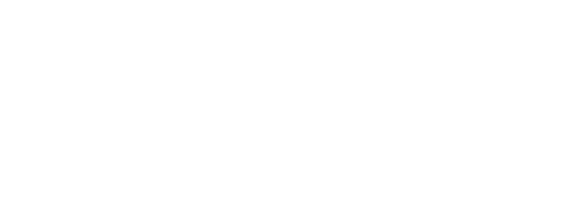 Una persona con un elmetto rosso e un giubbotto ad alta visibilità si trova di fronte alla facciata di un moderno edificio a più piani.