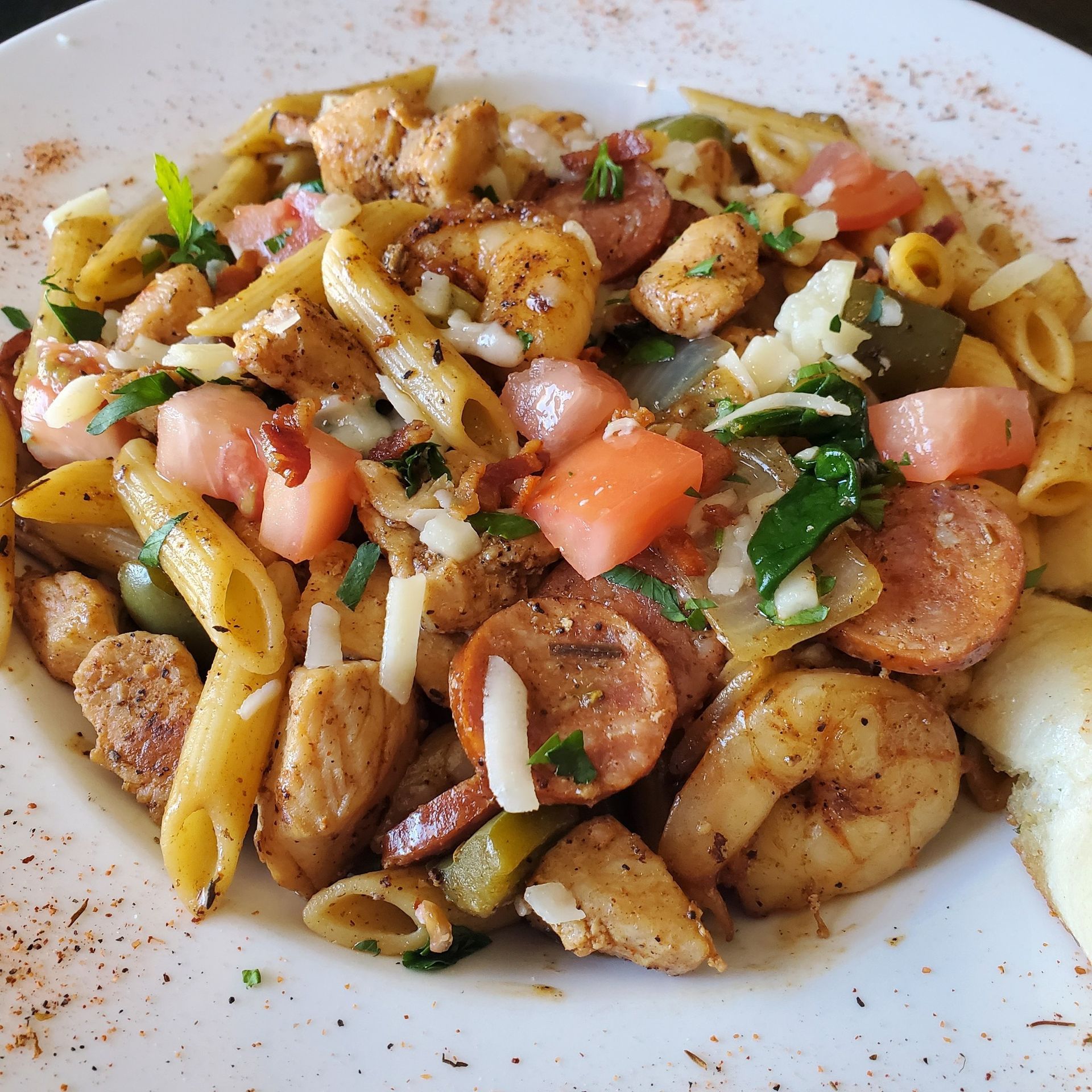 Pasta dish with chicken, sausage, shrimp, tomatoes, peppers, and cheese.